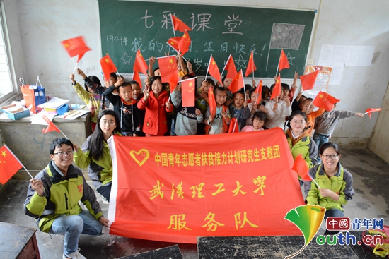 图为长沟小学的孩子们与武汉理工大学研支团成员和国旗合影。武汉理工大学研支团 供图