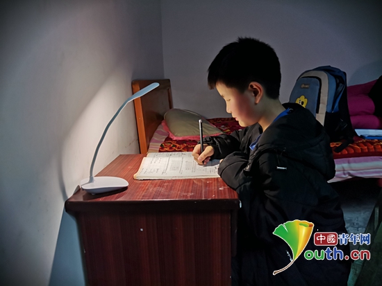 图为弄塘小学的孩子在台灯下认真地写作业.