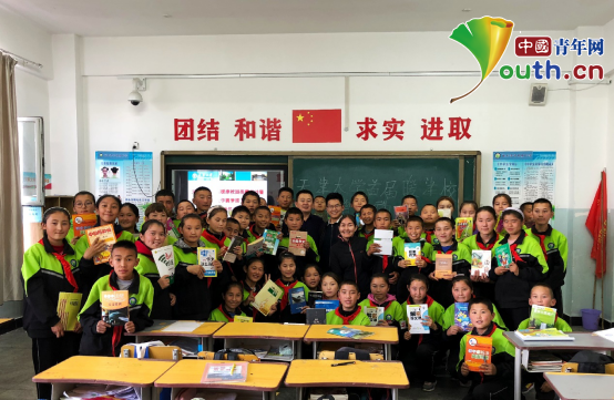 天津大学第二十届研究生支教团团长许全军与孩子们在暖津暖校捐赠书籍活动中合影。许全军 供图