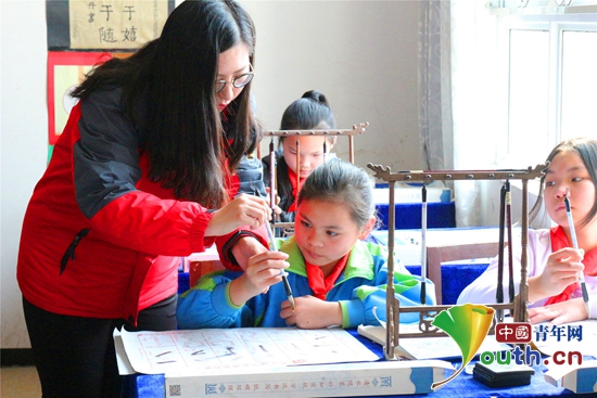 江西师范大学研支团成员在课堂上教留守儿童学写毛笔字。曾祥钰 供图